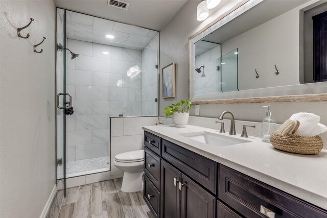 bathroom featuring a stall shower, visible vents, toilet, wood finished floors, and vanity