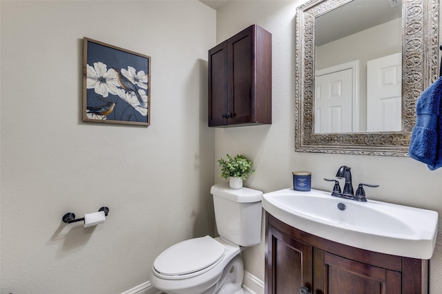 half bath featuring baseboards, a sink, and toilet