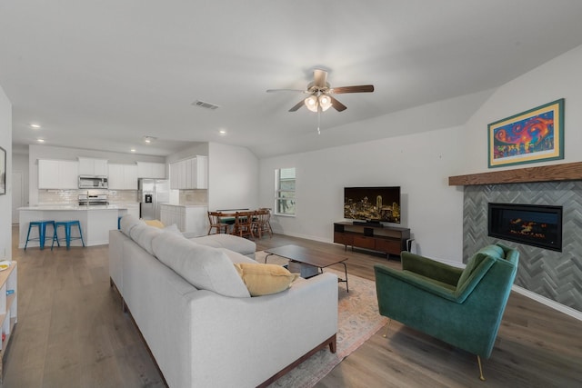 living room with baseboards, visible vents, vaulted ceiling, and wood finished floors