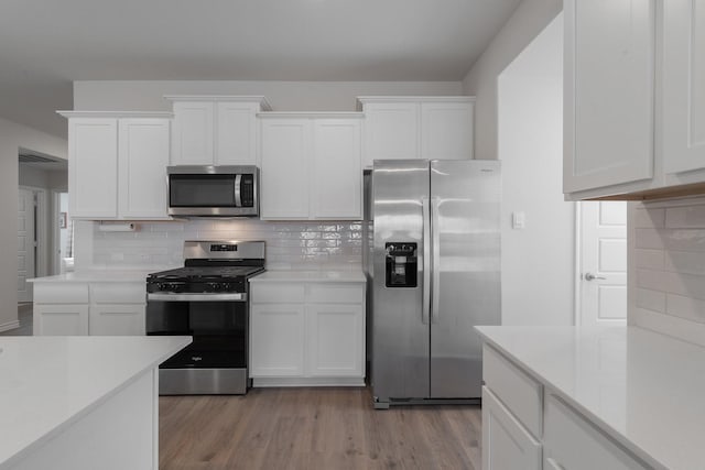 kitchen featuring stainless steel appliances, light countertops, light wood-style flooring, backsplash, and white cabinets