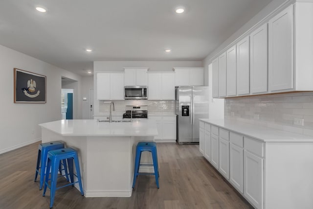 kitchen with appliances with stainless steel finishes, a breakfast bar, a sink, and wood finished floors