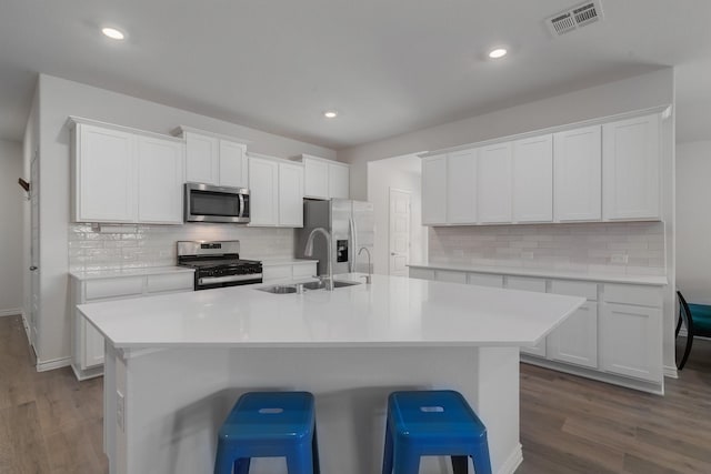 kitchen with appliances with stainless steel finishes, dark wood-style flooring, a sink, and visible vents