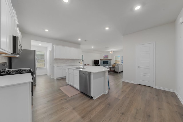 kitchen with tasteful backsplash, appliances with stainless steel finishes, open floor plan, white cabinetry, and a sink