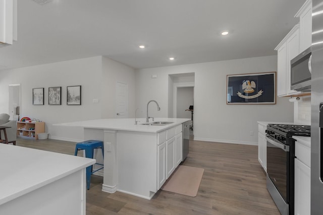 kitchen with dark wood-style floors, stainless steel appliances, a sink, and white cabinets