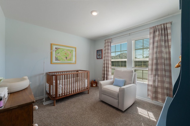 bedroom featuring carpet flooring, a crib, and baseboards