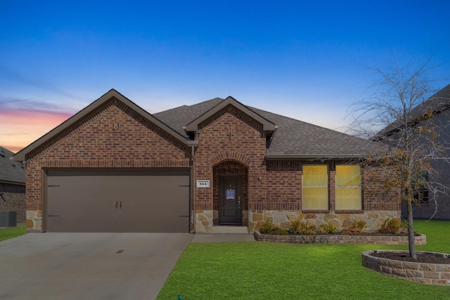 view of front facade featuring a shingled roof, a front lawn, an attached garage, and brick siding