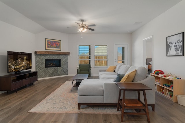 living area featuring lofted ceiling, a fireplace, wood finished floors, a ceiling fan, and baseboards