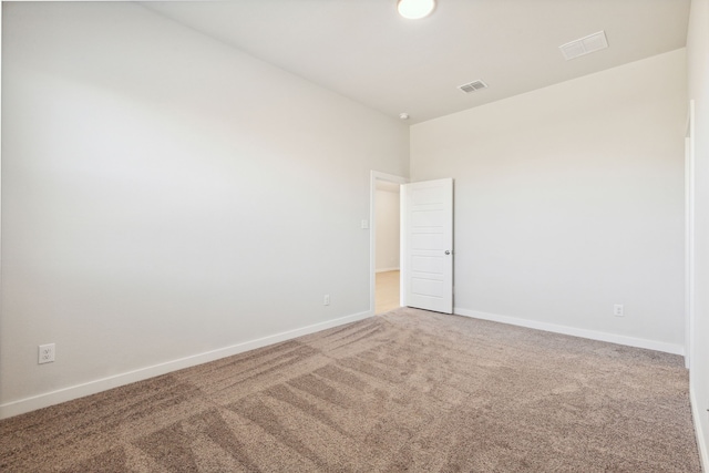 carpeted spare room with visible vents and baseboards