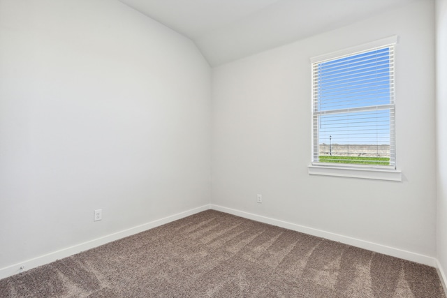 spare room with lofted ceiling, dark carpet, and baseboards