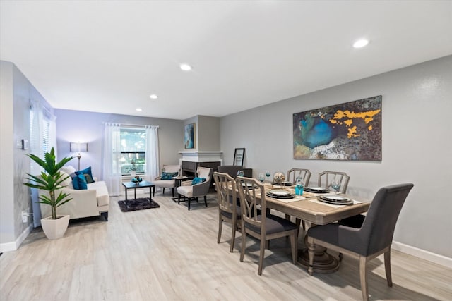 dining space with a fireplace, baseboards, and wood finished floors