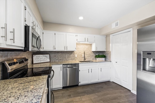 kitchen featuring white cabinets, light stone countertops, stainless steel appliances, and a sink