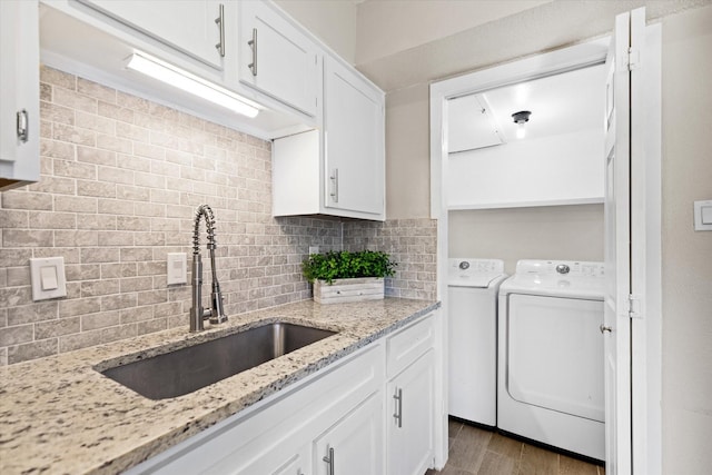 kitchen with white cabinets, a sink, decorative backsplash, and separate washer and dryer