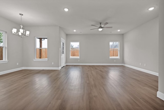 unfurnished living room with ceiling fan with notable chandelier, baseboards, dark wood finished floors, and recessed lighting