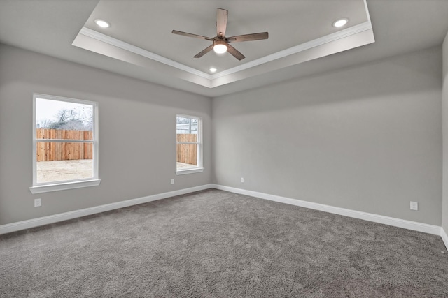 empty room with baseboards, a tray ceiling, and ornamental molding