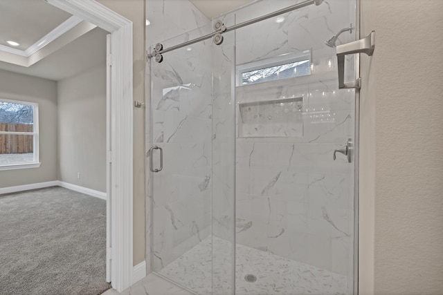 bathroom with ornamental molding, a marble finish shower, a wealth of natural light, and baseboards