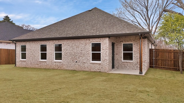 back of property featuring a yard, a shingled roof, and brick siding