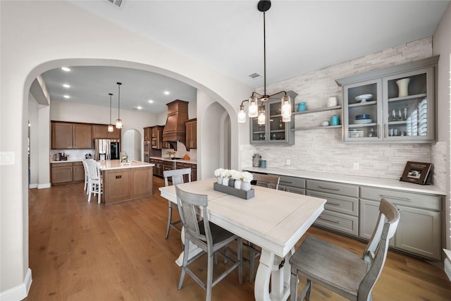 dining space with arched walkways, wood finished floors, visible vents, and recessed lighting