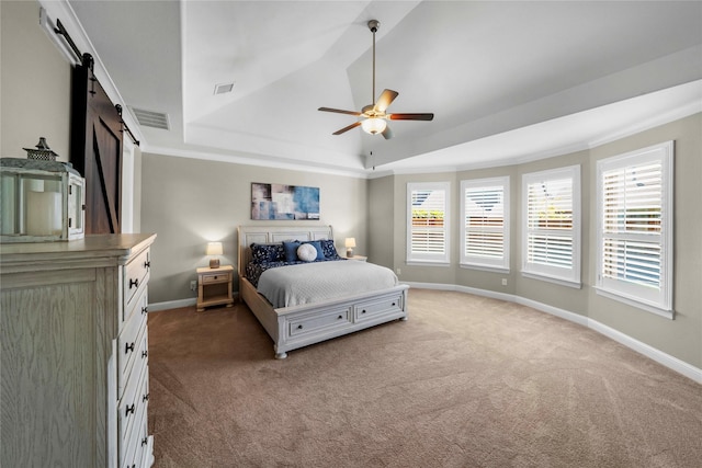 bedroom with a raised ceiling, visible vents, baseboards, and a barn door