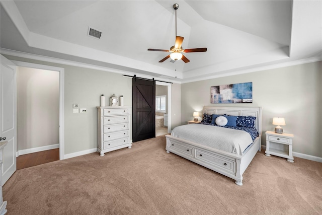 bedroom featuring carpet, a raised ceiling, visible vents, and a barn door