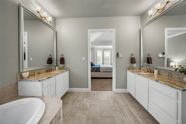 bathroom featuring ensuite bath, two vanities, and a sink