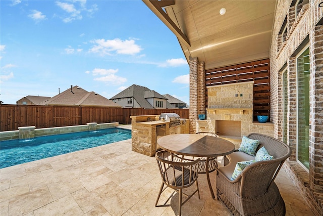 view of patio / terrace featuring a fenced in pool, a fenced backyard, a grill, and an outdoor kitchen