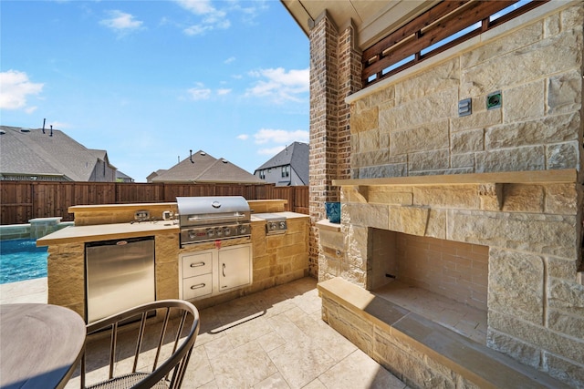 view of patio with an outdoor stone fireplace, a fenced backyard, area for grilling, and a grill