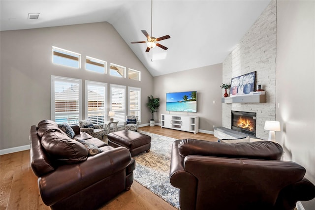 living room with high vaulted ceiling, a fireplace, baseboards, and wood finished floors