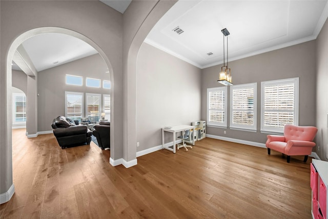 living area featuring arched walkways, wood-type flooring, visible vents, vaulted ceiling, and baseboards