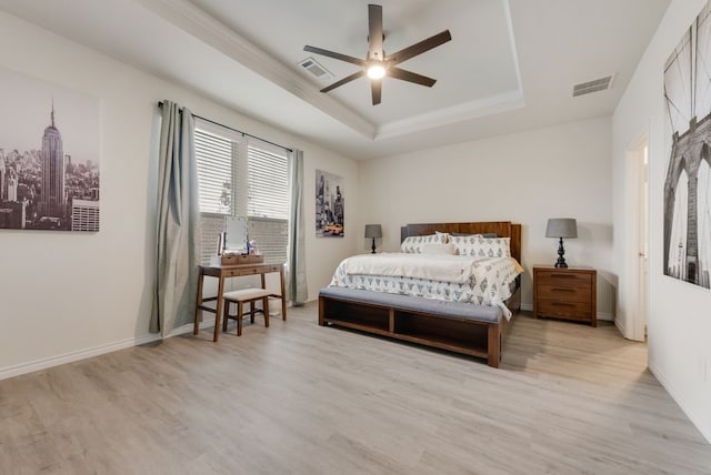 bedroom with light wood-type flooring, visible vents, and a raised ceiling