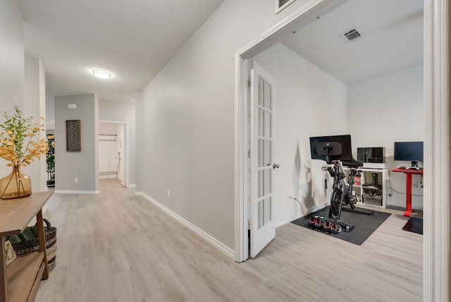 workout room with wood finished floors, visible vents, and baseboards