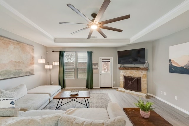 living area featuring ceiling fan, wood finished floors, and a raised ceiling
