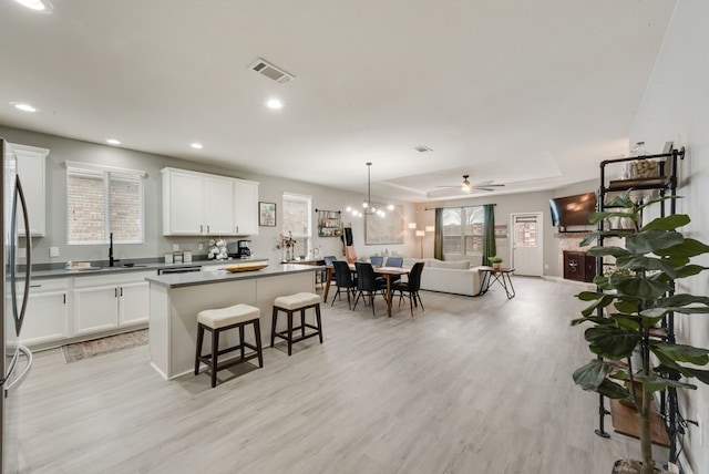 kitchen with a center island, open floor plan, a breakfast bar area, light wood-type flooring, and visible vents