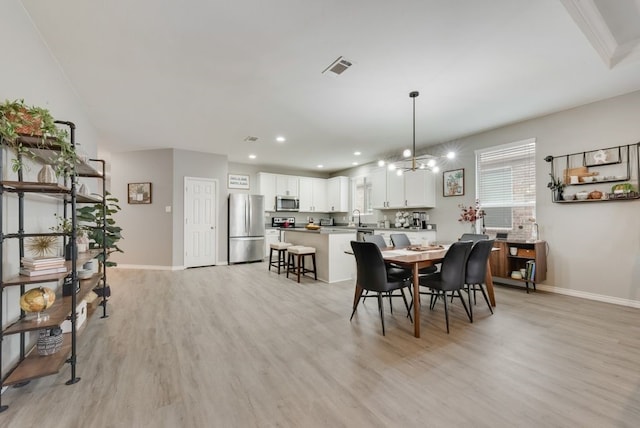 dining area featuring light wood-type flooring, baseboards, a notable chandelier, and visible vents