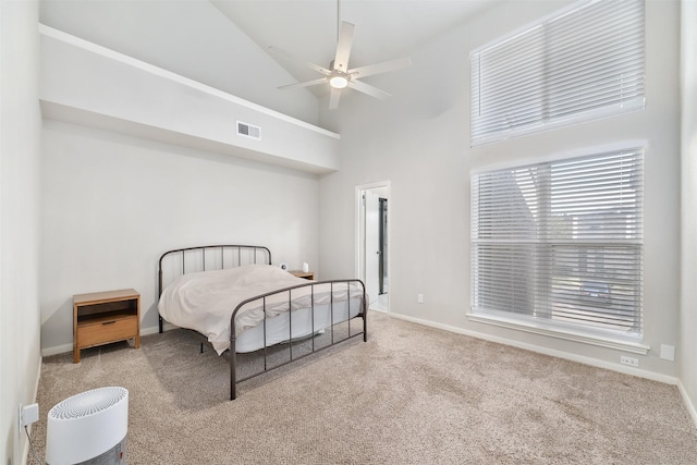 carpeted bedroom with high vaulted ceiling, baseboards, visible vents, and ceiling fan