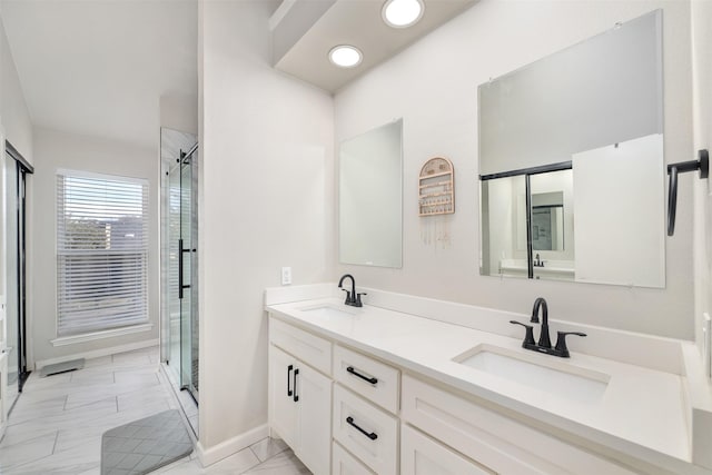 bathroom with double vanity, marble finish floor, a shower stall, and a sink