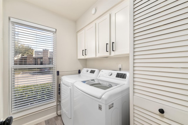 laundry area with wood finished floors, washing machine and clothes dryer, and cabinet space