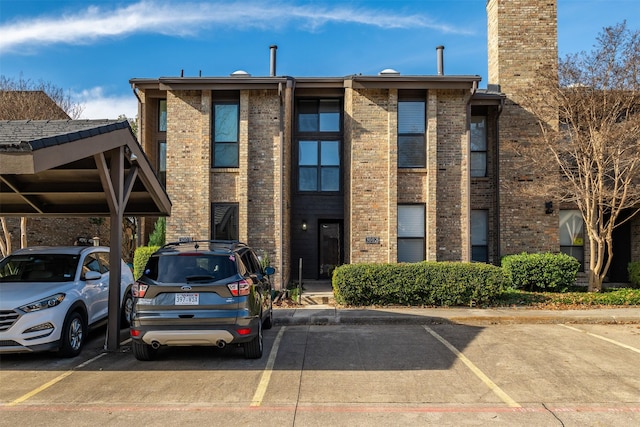 view of building exterior featuring covered and uncovered parking