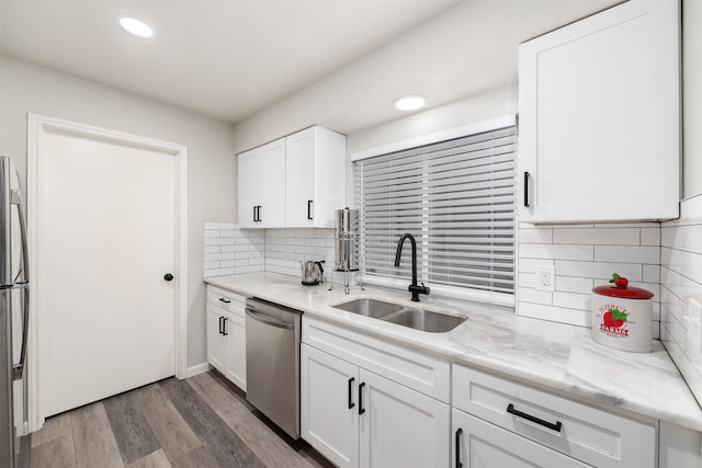 kitchen featuring stainless steel appliances, wood finished floors, a sink, and white cabinets