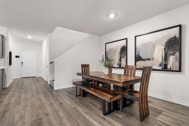 dining space with stairs, baseboards, and wood finished floors