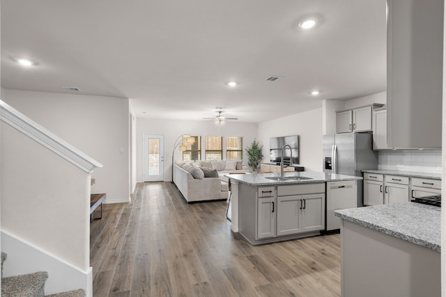 kitchen featuring dishwashing machine, light wood-style flooring, a sink, open floor plan, and stainless steel refrigerator with ice dispenser