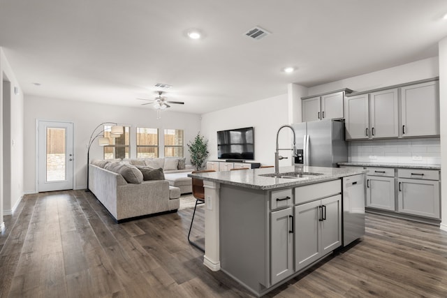 kitchen with stainless steel appliances, a sink, visible vents, open floor plan, and gray cabinets