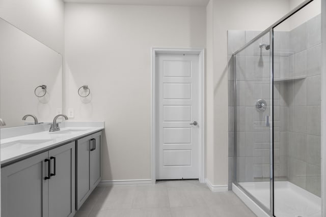 bathroom with double vanity, a stall shower, baseboards, and a sink