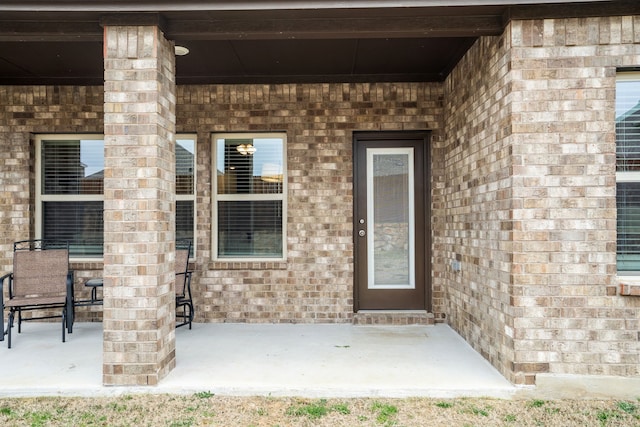 property entrance with brick siding and a patio area