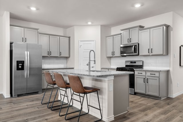 kitchen featuring wood finished floors, appliances with stainless steel finishes, a sink, and gray cabinetry