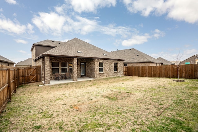 back of house featuring brick siding, a lawn, a patio area, and a fenced backyard