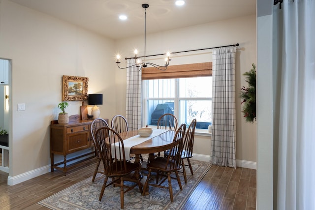 dining space with baseboards, wood finish floors, recessed lighting, and a notable chandelier