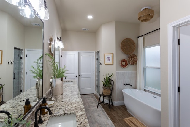 bathroom featuring a sink, wood finished floors, visible vents, a freestanding bath, and a stall shower