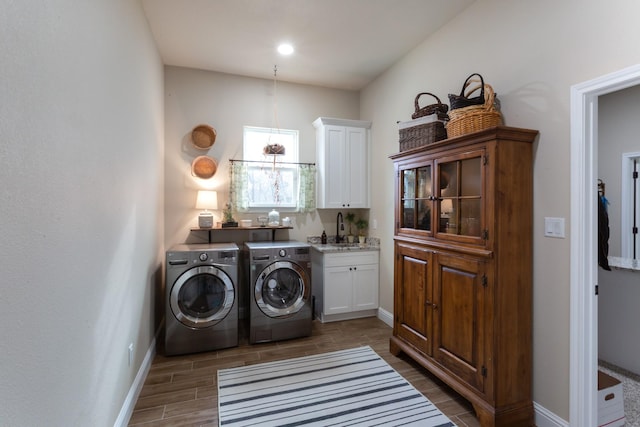 laundry area with cabinet space, baseboards, wood tiled floor, separate washer and dryer, and a sink