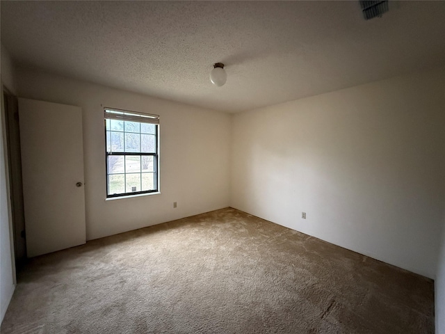 unfurnished room featuring carpet floors, visible vents, and a textured ceiling