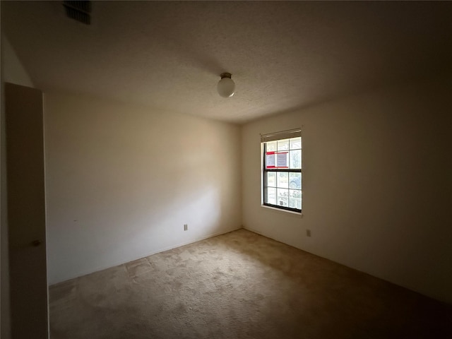 empty room featuring carpet, visible vents, and a textured ceiling